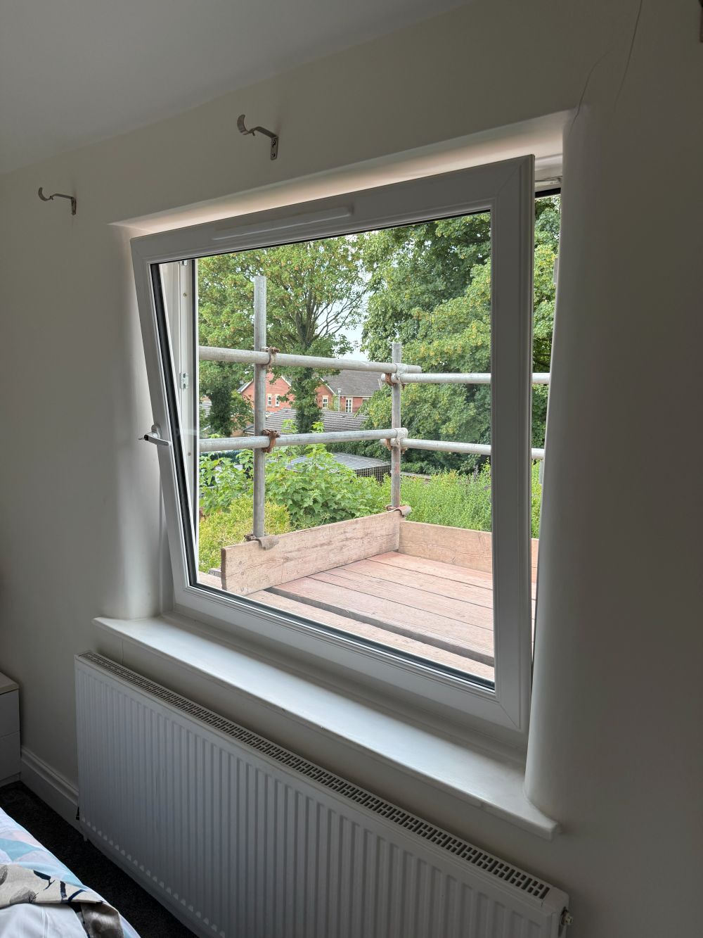 White tilt-and-turn window in ventilation position overlooking a garden in Altrincham