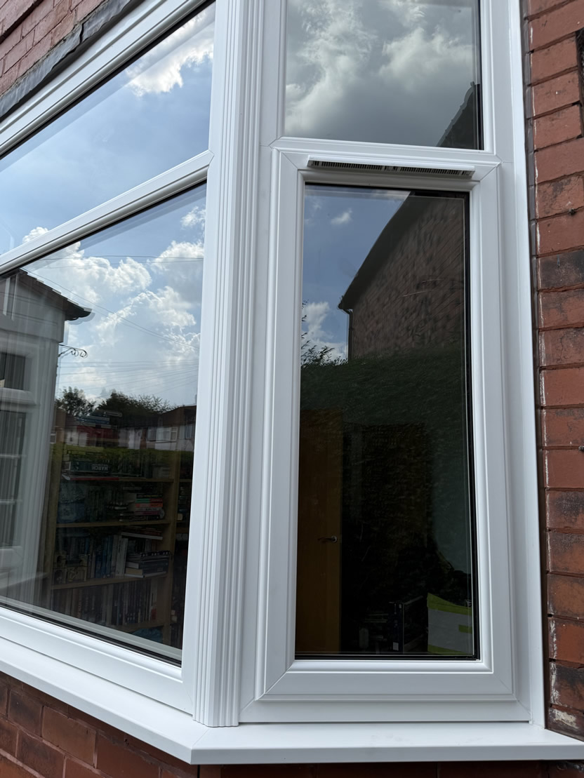 Exterior detail of white replacement bay window with large glazed panels in Altrincham