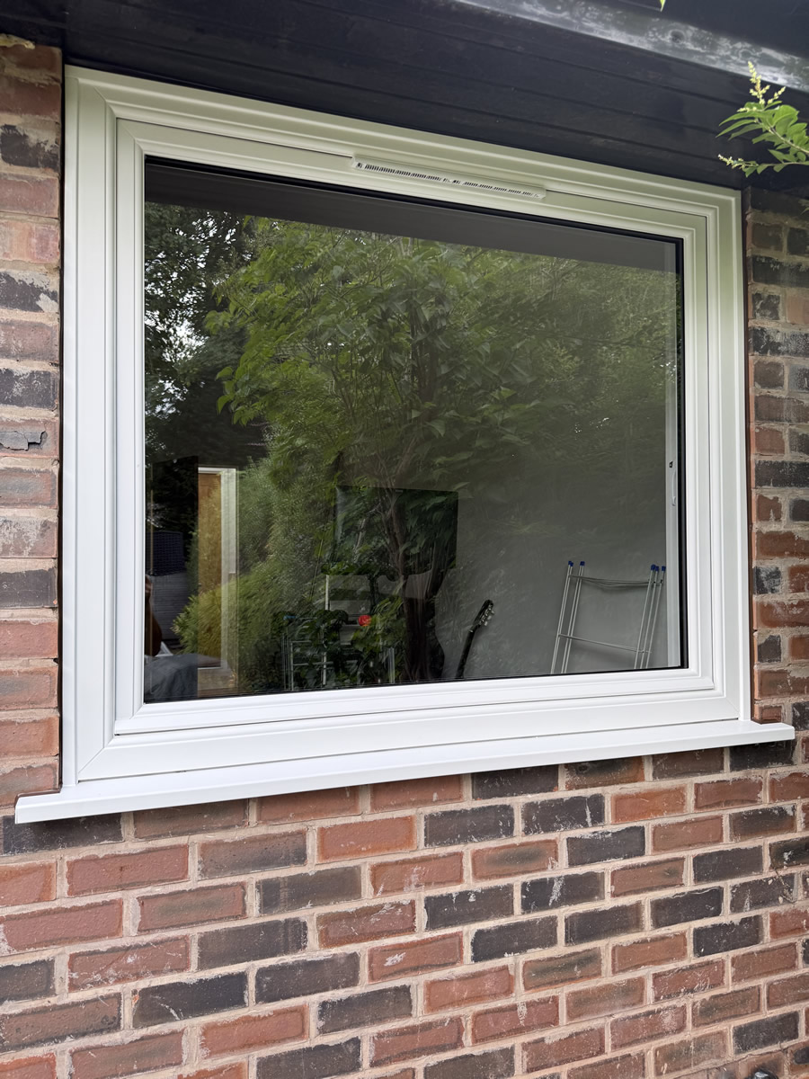 Large white garden-facing replacement window fitted to an Altrincham home