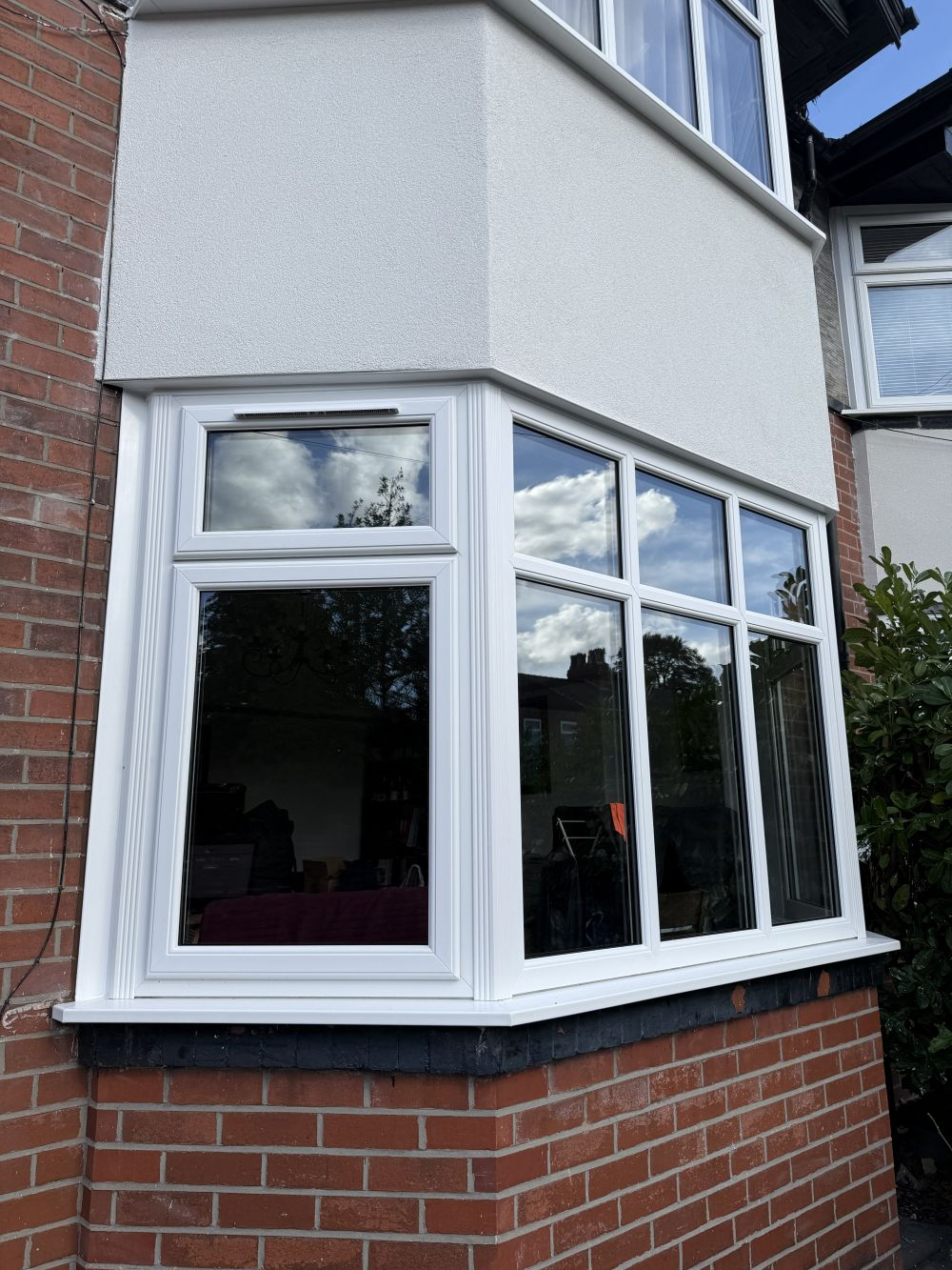 Close view of the white lower bay window, sill and smooth rendered middle section.