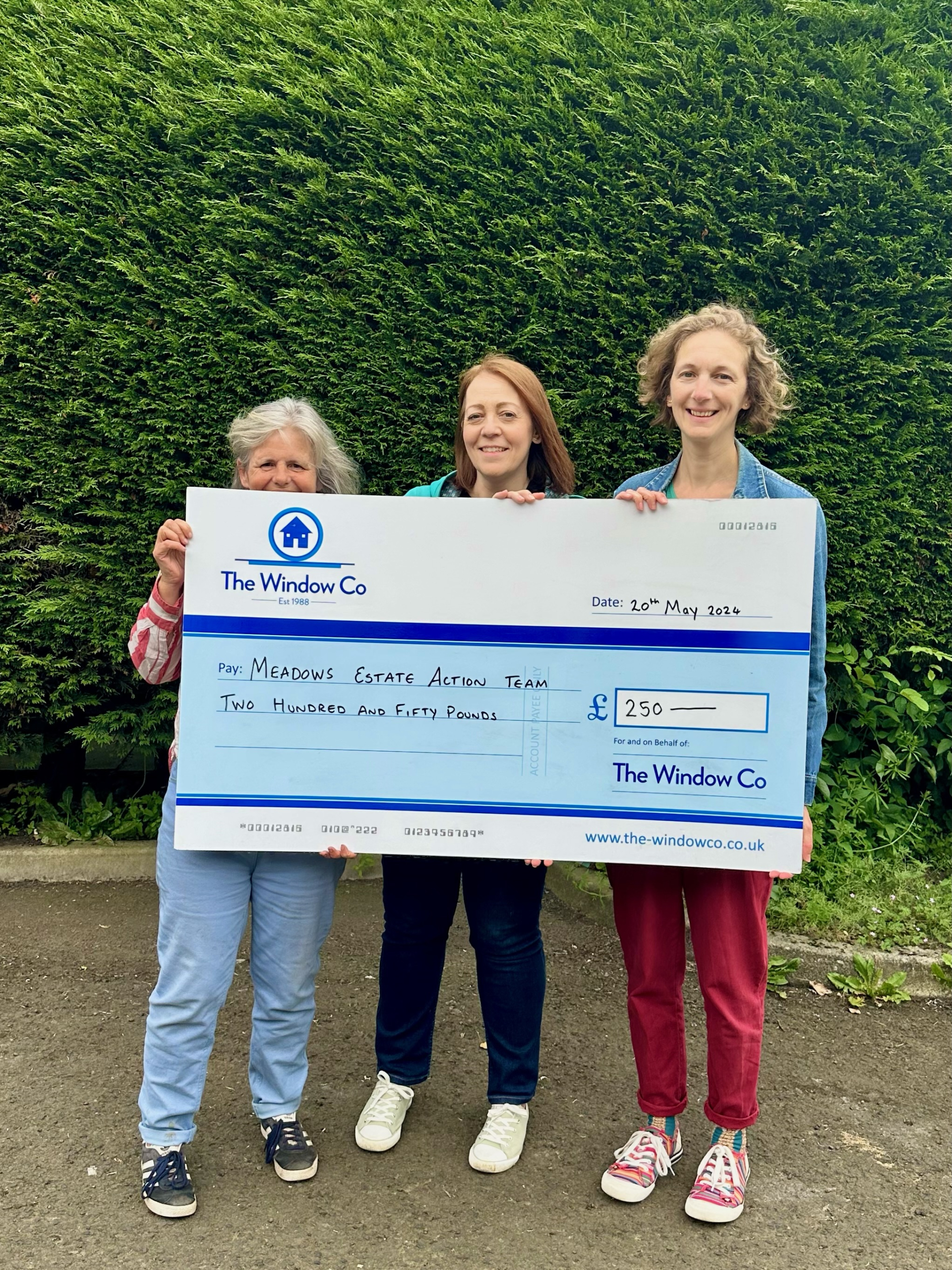 photo of check held by staff donating to meadows estate action team - The Windows Co