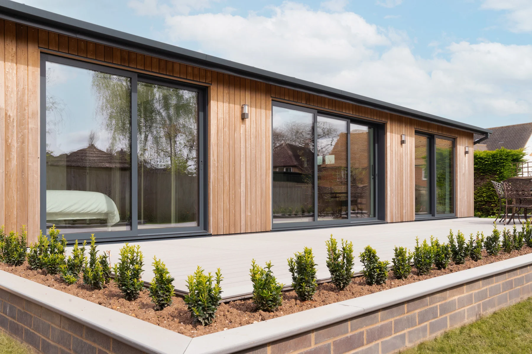 Modern anthracite grey sliding doors on a contemporary wooden building exterior. - The Window Co