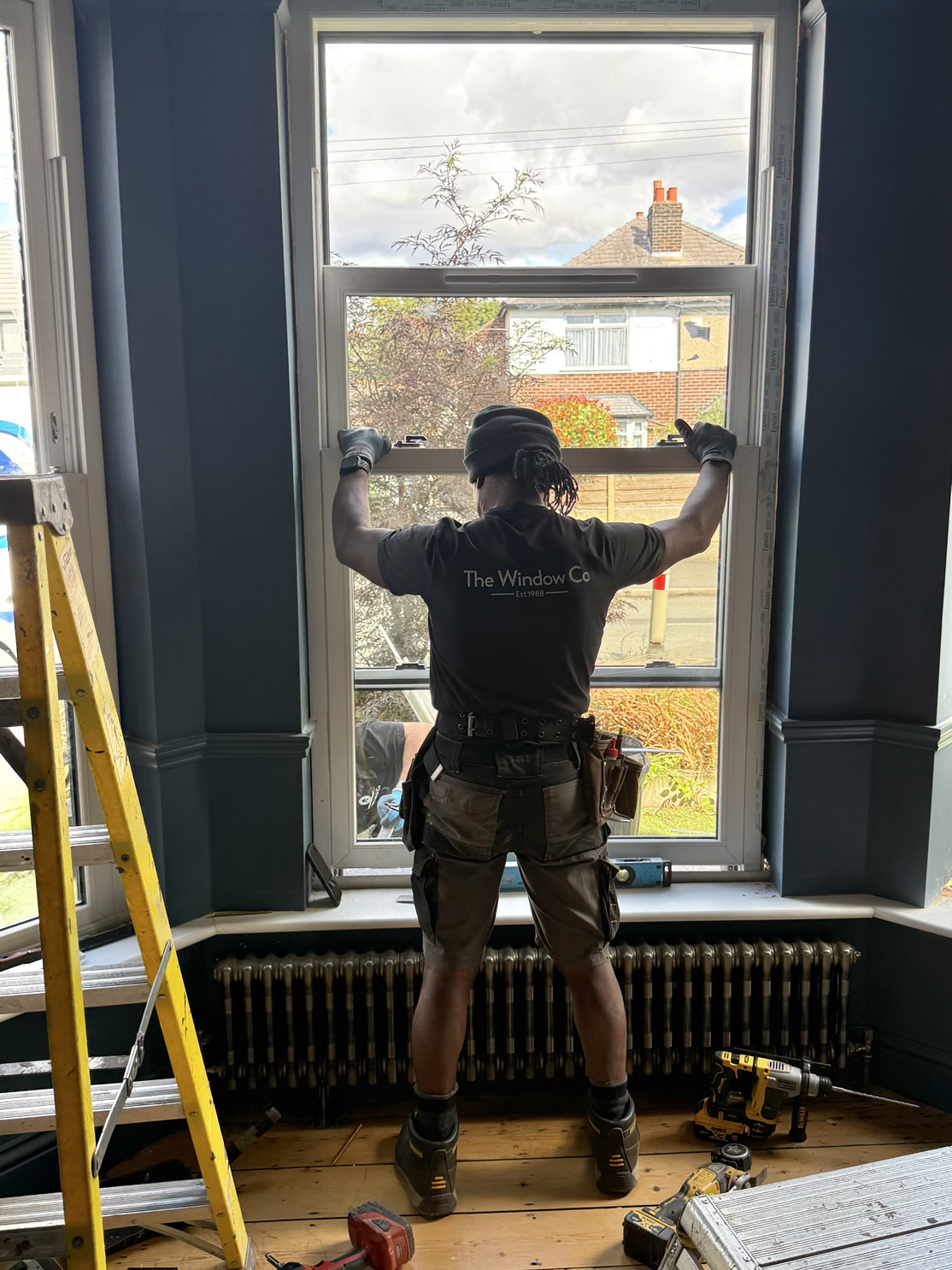 A Window Company installer fitting a sash window from inside Helen's home in Sale.